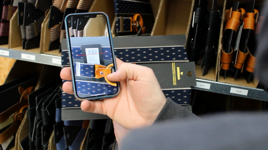 Persoon scant riem in magazijn met smartphone app
