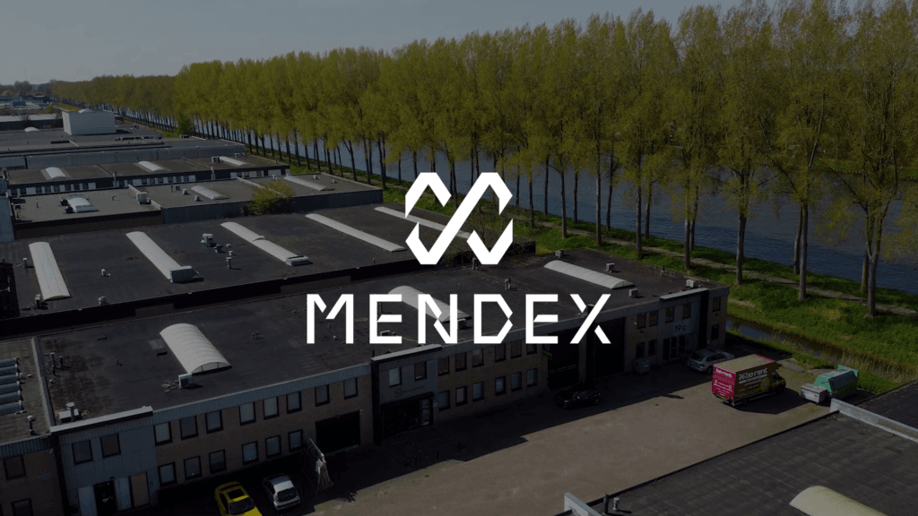Luchtfoto van industrieterrein naast rivier met logo Mendex